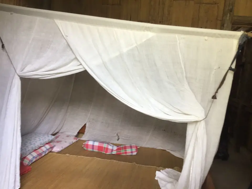 A treated mosquito net above a bed, malaria prevention