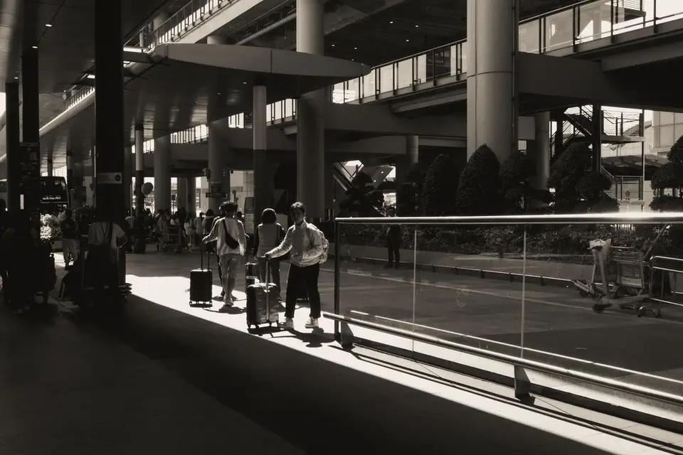 Silhouettes of travellers and their luggage in an airport hall filled with light